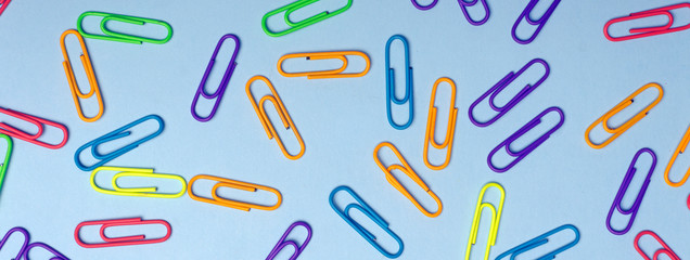 Color clips minimal concept. Colored paper clips on a colored background