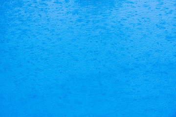 Image to use as background of rain falling on the water of a lake of transparent blue waters during a summer storm.