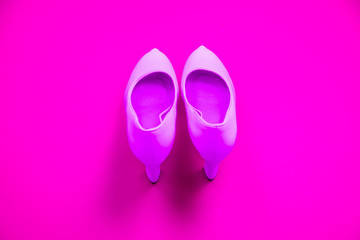 Pink high heeled shoes on pink purple background - top view - heels pointing up