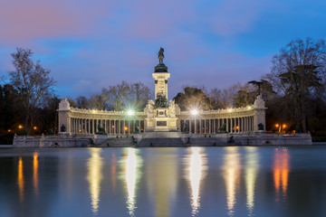 Fototapeta na wymiar Night cityscape with lights at the memorial in Retiro city park, Madrid, Spain.