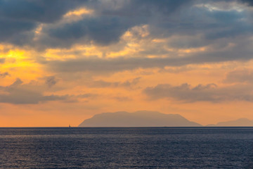 Fototapeta na wymiar Picturesque sunset over Tyrrhenian Sea in Milazzo town, Sicily, Italy. Aeolian Islands (Italian: Isole Eolie), volcanic archipelago on the north of Sicily on the background