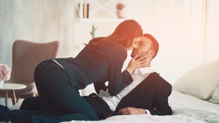 The business couple in suits making love on the bed on a sunny background