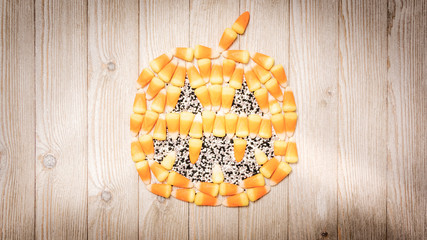 Candy corn forms a pumpkin on wood