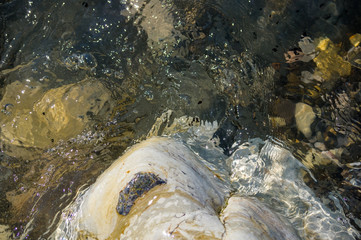 pebble stones on the sea beach, the rolling waves of the sea with foam