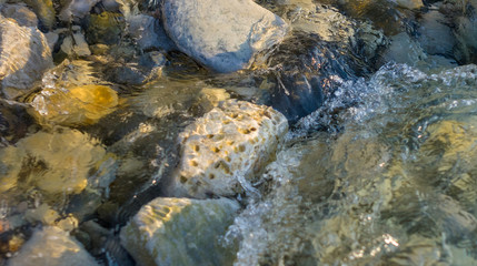 pebble stones on the sea beach, the rolling waves of the sea with foam