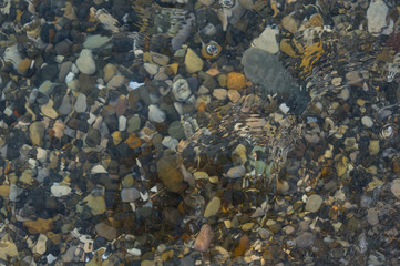 pebble stones on the sea beach, the rolling waves of the sea with foam