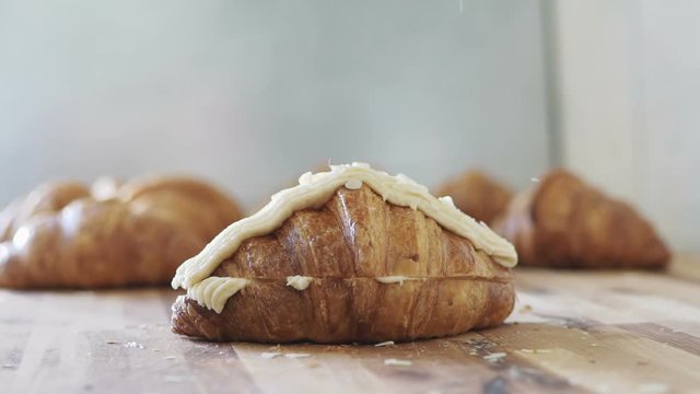 Almond slices sprinkling onto a croissant. Slow motion 100 fps