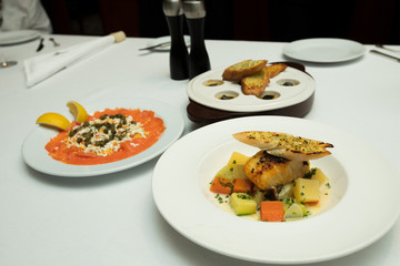 Food set course on white table with salmon sashimi smoked, garlic bread shell, and grill fillet sea bass fish which is very delicious for couple dinner special occasion