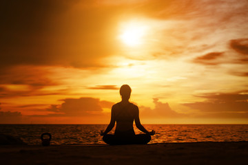 woman practicing yoga during surrealistic sunset at the seaside. healthy concept and workout.