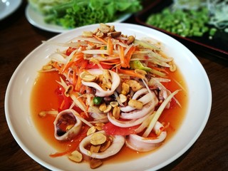 Thai style papaya salad with fresh sliced squid or Som Tam Thai recipe . The papaya salad is one of the most popular food in Thailand.  