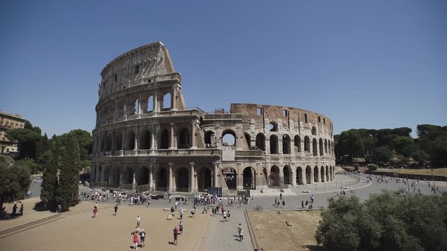 The Colosseum or Coliseum, Rome, Italy, time lapse of sight in summer day at clear sky background. People walk and take pictures