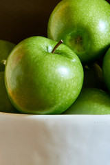 Green Granny Smith cooking apples in a white bowl.