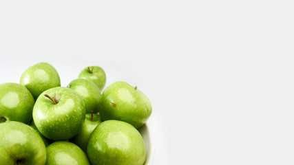 Green Granny Smith cooking apples in a white bowl from above against a light grey background with space for copy.