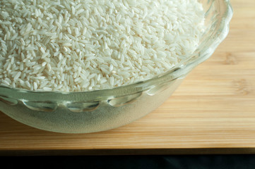 Raw rice in a bowl on a wooden cutting board