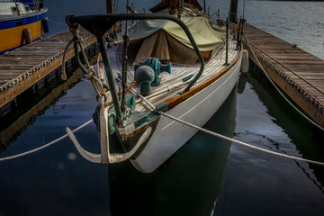 Sailing boat w/anchor, between 2 docks on a reflective crystal sea.