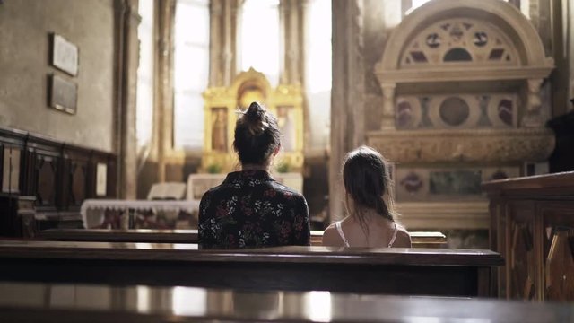 Mother and Daughter is Praying in Catholic Church