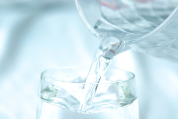 Pour pure water from a bottle of mineral water into a glass.Health concept