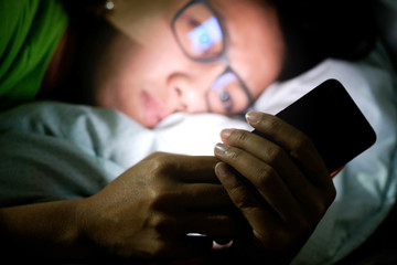 woman does not sleep and is stressed at night. She uses and looks smartphone in the bedroom without...