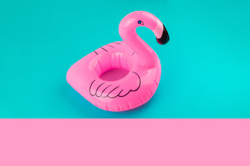 Inflatable mini flamingo on pastel blue and pink background. Pool float party, trendy summer concept. Flat lay, copy space.