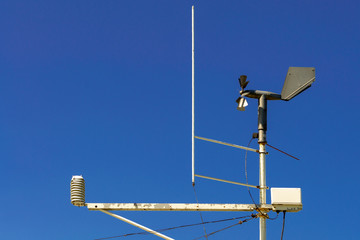 Obraz premium Weathervane weather station with a propeller and other measuring devices against a blue sky. Front view