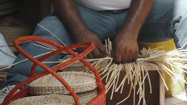 Close up of man's hands making a basket out of straw