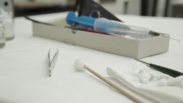 Closeup of laboratory tools on table - tweezers, cotton wool, paint brush and injection with needle