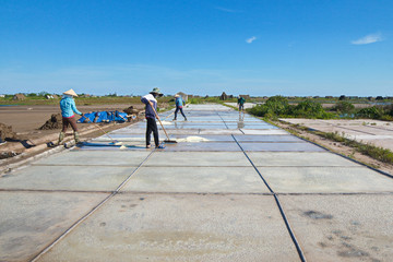 BACH LONG SALT FIELDS, NAMDINH, VIETNAM - JUNE 9, 2019: Salt workers working on salt fields. This location used to be the largest salt production site in Northern Vietnam but now almost abandoned.