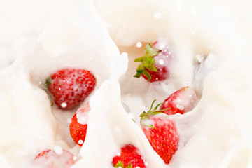 Red natural ripe strawberries falling into milk cream