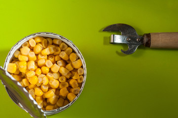 A can of corn canned on a black background, opened with a special opener knife