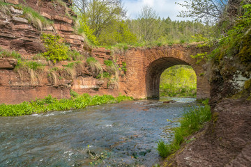 Fototapeta na wymiar Mountain river flowing through stone bridge arch