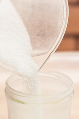 Pouring white sugar into a smaller container for ease of use