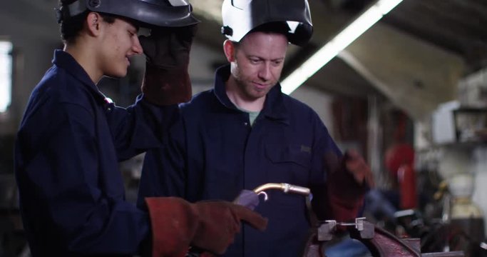 4K Experienced welder giving 'on the job' training to young apprentice. Slow motion.