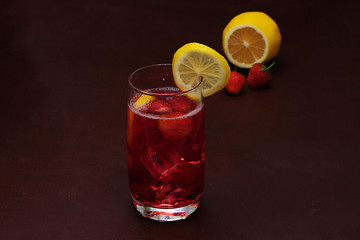 Drink with ice from strawberries on a dark background. Fresh strawberry cocktail. Fresh summer cocktail with strawberry and ice cubes. Glass of strawberry soda drink on dark background.
