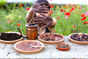 woman is manufacturing seed balls or seed bombs on a wooden table