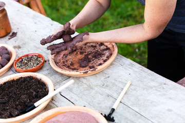 woman is manufacturing seed balls or seed bombs on a wooden table