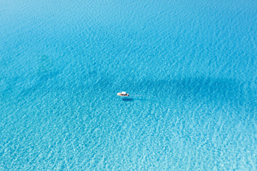 View from above, stunning aerial view of an inflatable boat with tourists on board sailing on a beautiful turquoise clear water. Spiaggia La Pelosa (Pelosa beach) Stintino, Sardinia, Italy.