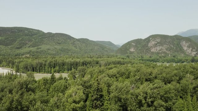 An aerial, cinematic, moving view of the surrounding  hills and mountains, shot in Terrace, B.C. Canada during the summer months on a sunny day.