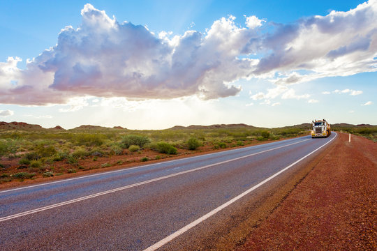 Road train with unbranded carriages on Australian outback highway. Pilbara mining region, Western Australia.