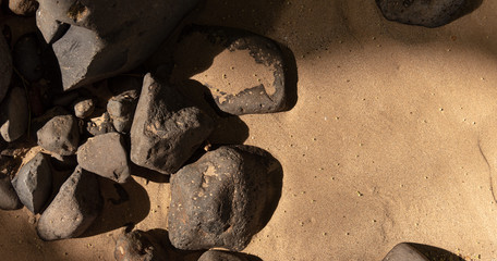 Warm sand with negative space with black volcanic rock