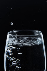A glass of water on a black background. Close-up