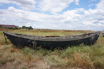 An old wooden punt-boat, thrown in a meadow in the grass.
