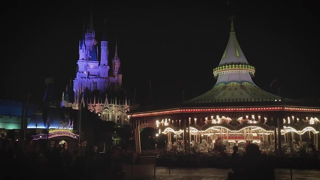 People walking through a lit up theme park at night