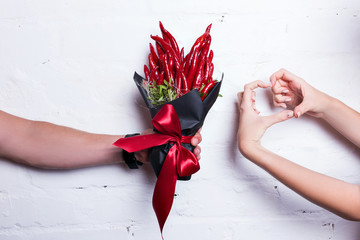 The original unusual edible bouquet of vegetables and fruits on white. Female hand shows heart.
