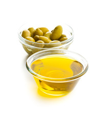 Green olives and olive oil in glass bowl.