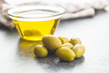 Green olives and olive oil in glass bowl.