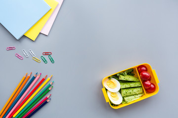 School supplies and lunch box with sandwich and vegetables. Back to school. Healthy eating habits concept - background layout with free text space. Flat lay composition, mockup, top view