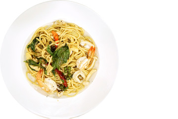 Top view seafood stir fried spicy spaghetti in white ceramic plate with copy space on white background.