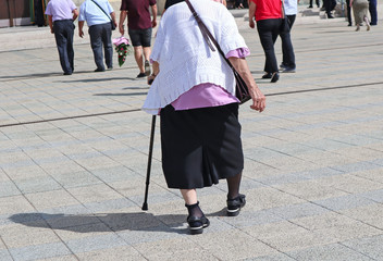Old woman and other people walk on the street