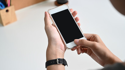 Close up Woman hand Using a Smart Phone with blank screen at desk.