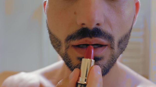 the guy with the beard paints his lips with red lipstick. man paints his lips.4k. 4k video
